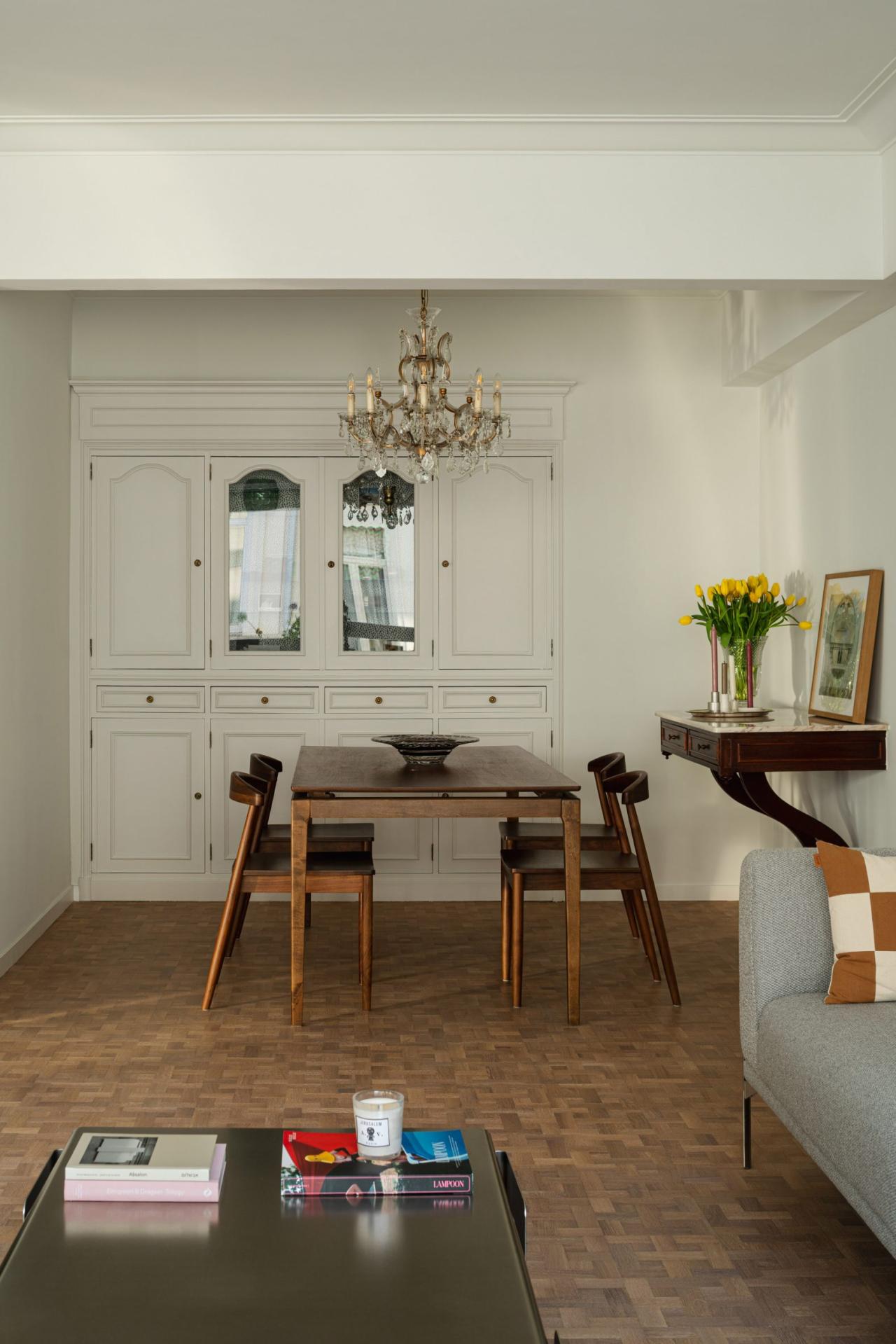 Zona de dining cu masa din lemn si candelabru de cristal