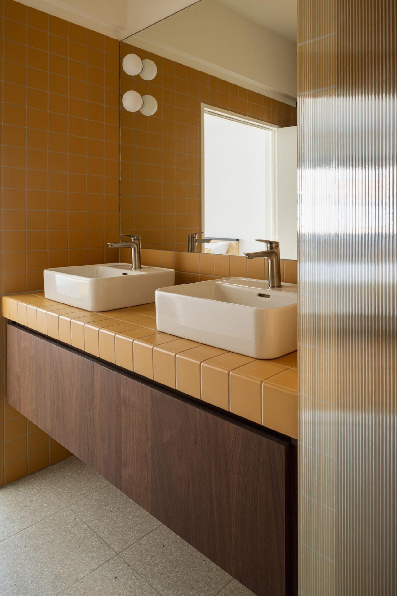 Baia principala cu blat faianta portocaliu-mustar si doua chiuvete albe