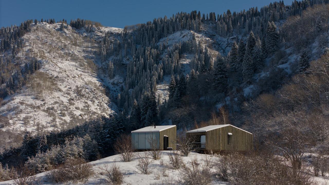 Cabanele AUM in peisajul montan din Almaty, inconjurate de paduri de conifere si zapada