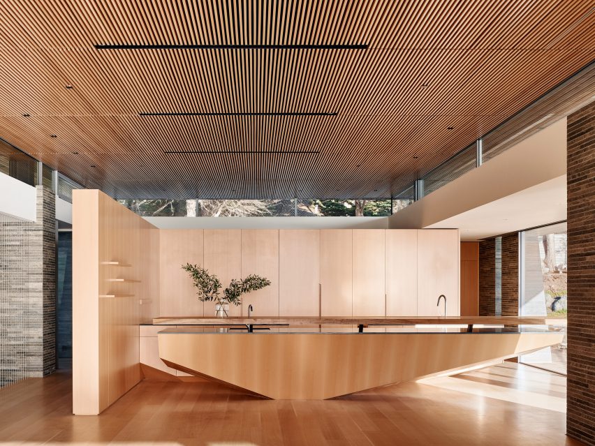 Bucataria cu insula sculptata din lemn si tavan cu lamele din teak si ferestre panoramice