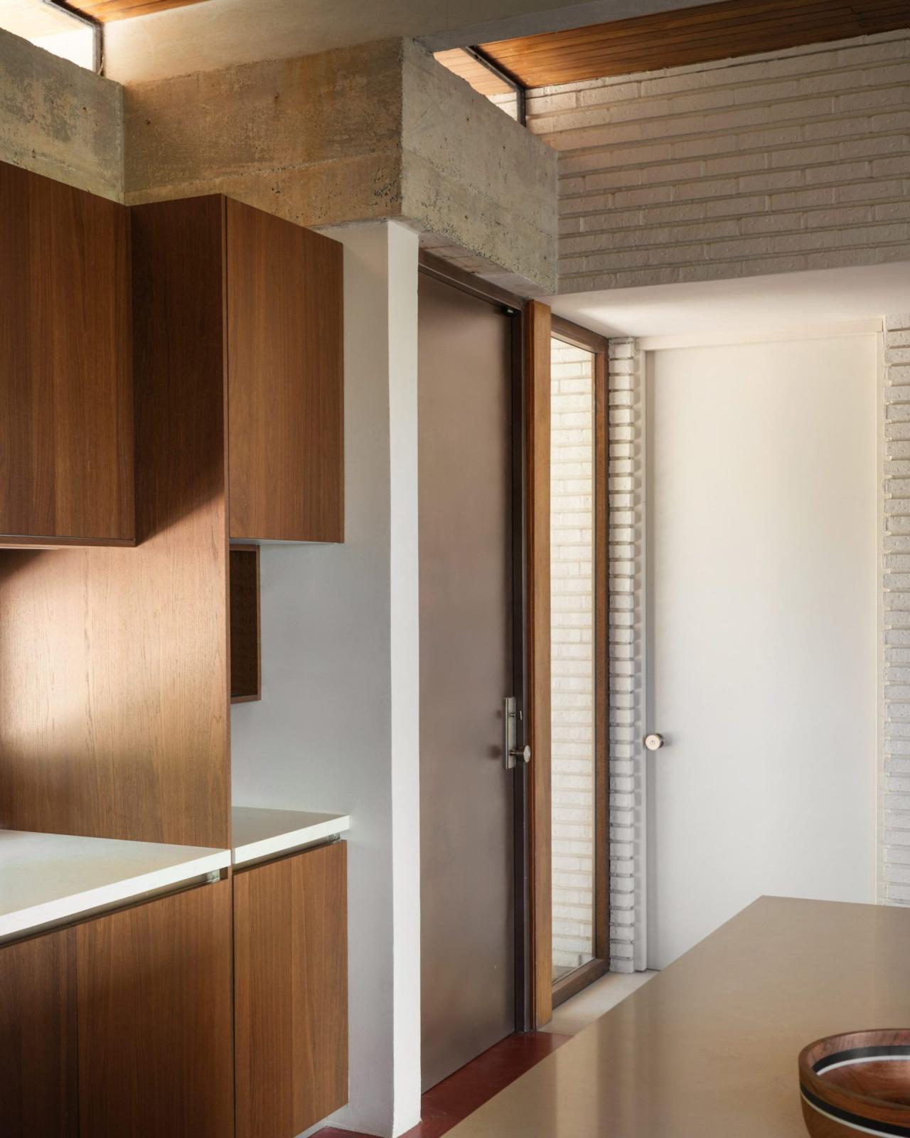 Bucatarie cu dulapuri din lemn de nuc, blat alb si structura din beton aparent cu luminatoare – foto Thibault Cartier / Dezeen