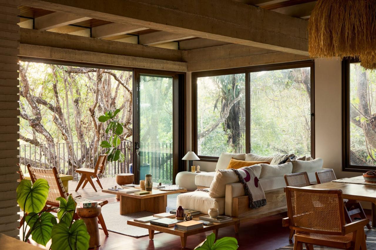 Living spatios cu canapea alba, mobilier din lemn si ferestre panoramice cu vedere la padurea tropicala – foto Thibault Cartier / Dezeen