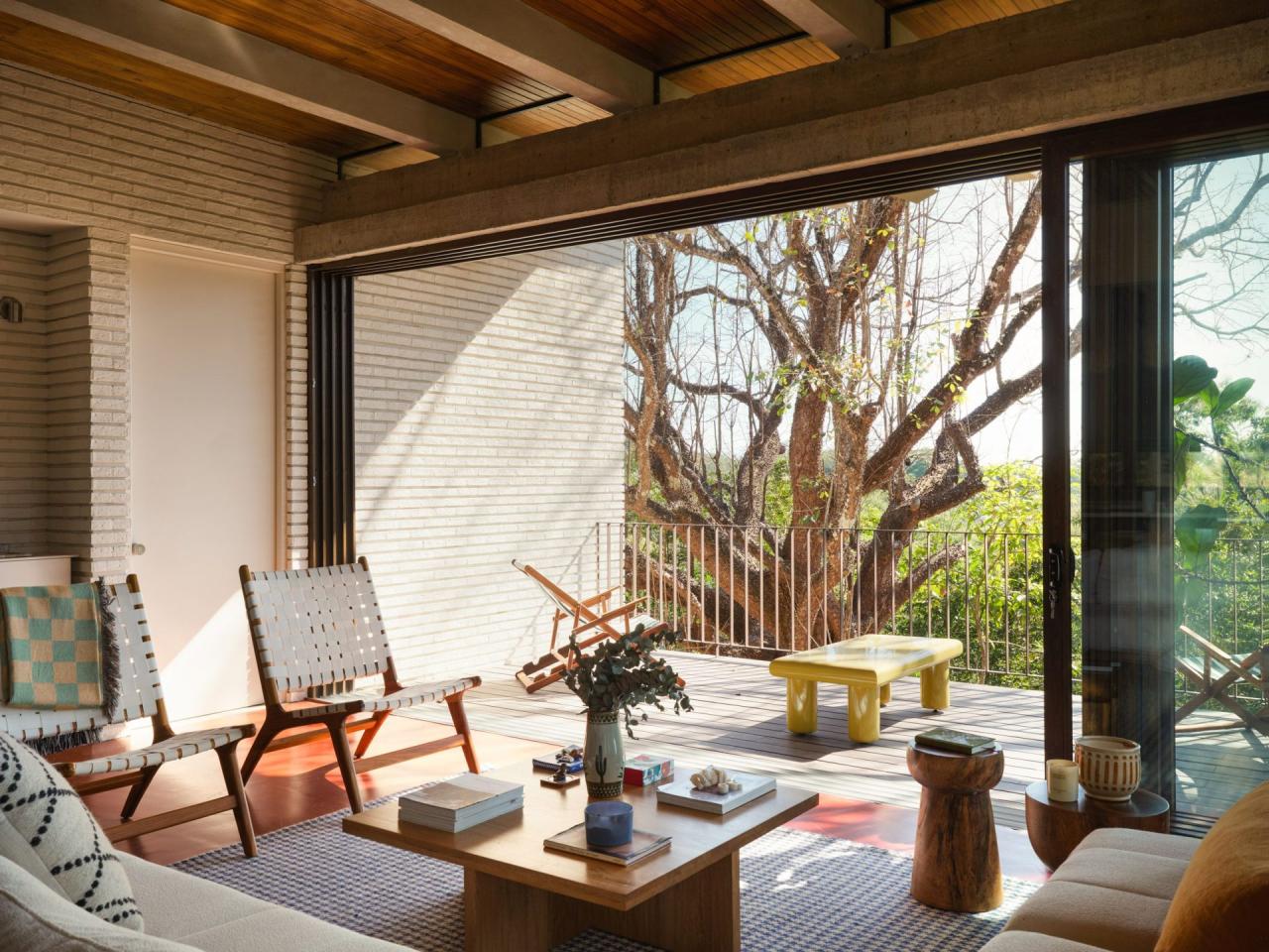 Zona de relaxare cu scaune din lemn impletit, terasa din lemn si vedere spre copacul pochote – foto Thibault Cartier / Dezeen