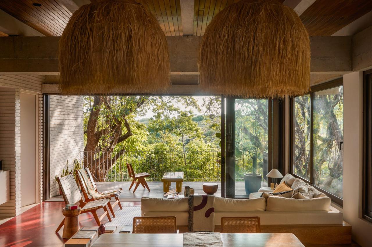 Living cu canapea alba, pendule din paie naturale si usi glisante spre terasa cu vegetatie luxurianta – foto Thibault Cartier / Dezeen