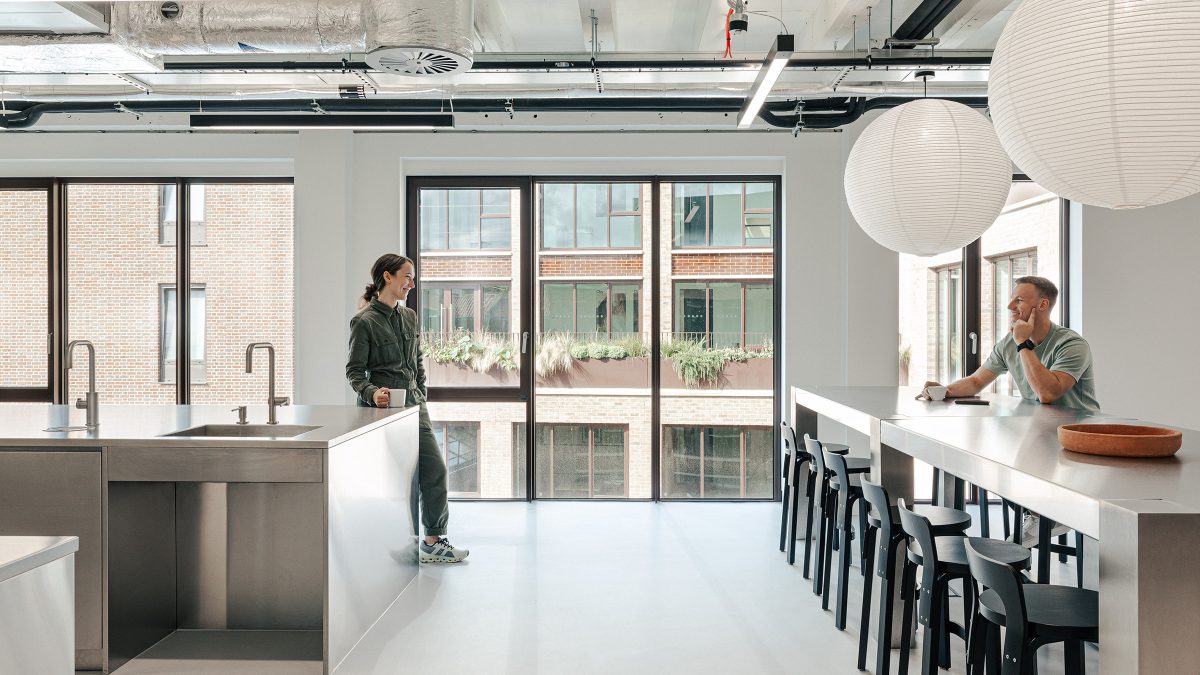 Tea point cu blat din inox, scaune bar negre si ferestre mari cu vedere spre cladirile din jur – foto Chris Wharton / M Moser Associates