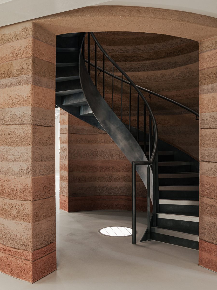 Scara spirala din metal negru in interiorul turnului din pamant compactat cu straturi de culori diferite – foto Chris Wharton / M Moser Associates
