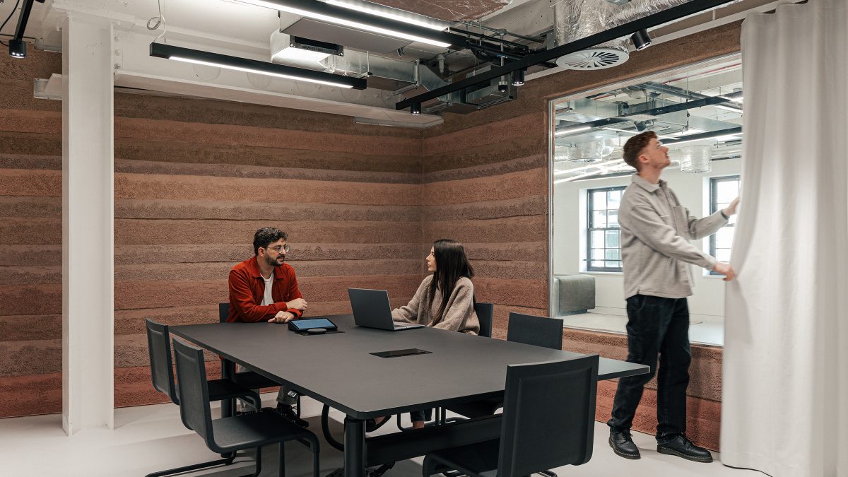 Sala de sedinta mica cu pereti integral din pamant compactat, masa neagra si perdea alba – foto Chris Wharton / M Moser Associates