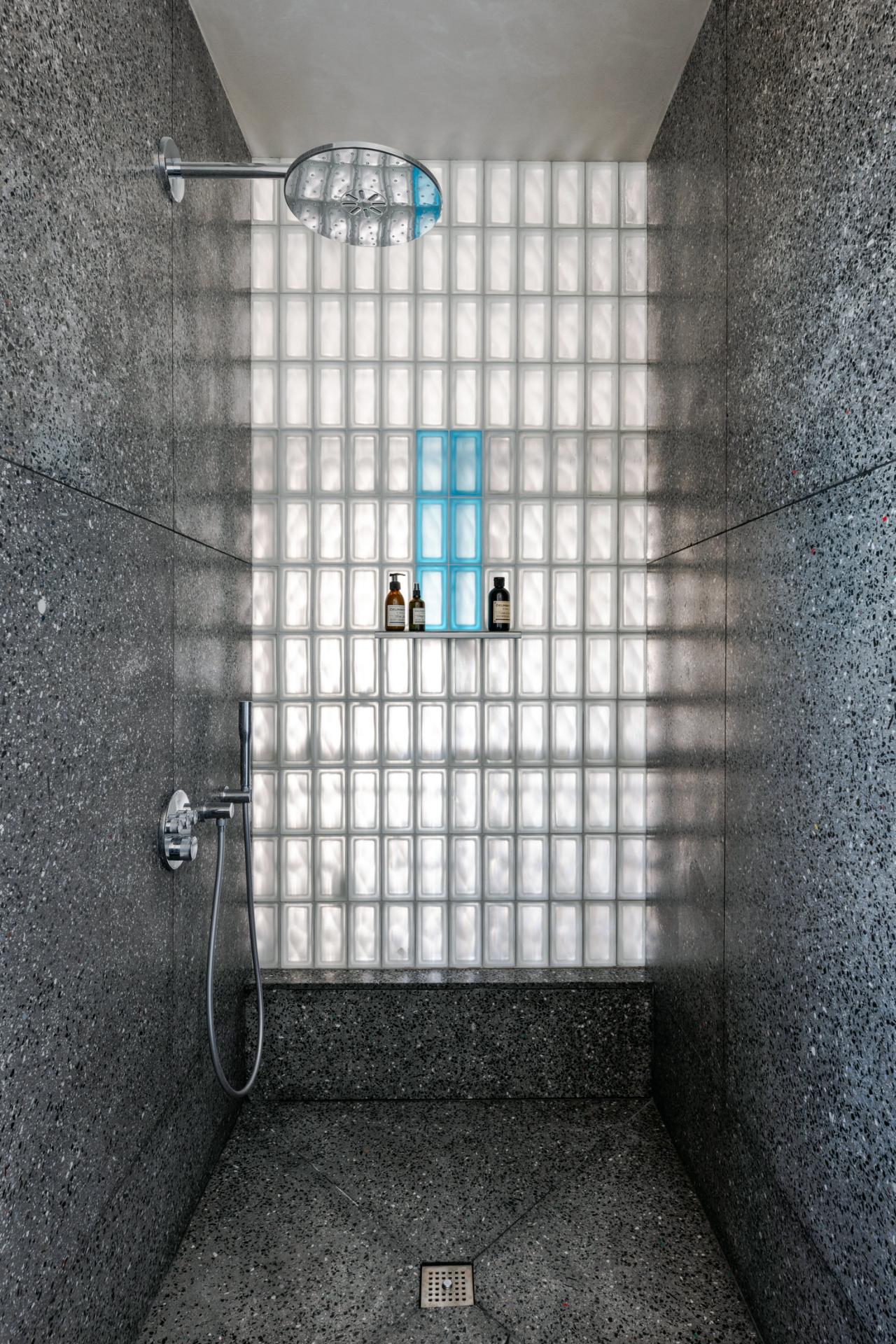 Dusul din terrazzo reciclat cu perete din caramizi de sticla si sase caramizi albastre in centru