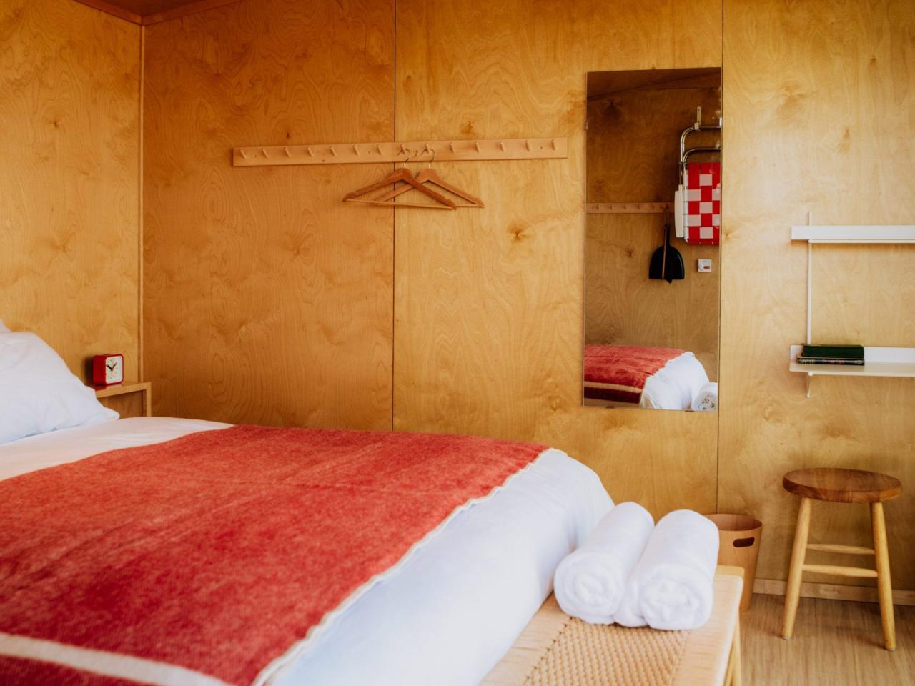 Interior cabana Prospect Berkshires cu pereti din lemn si pat cu cuvertura rosie