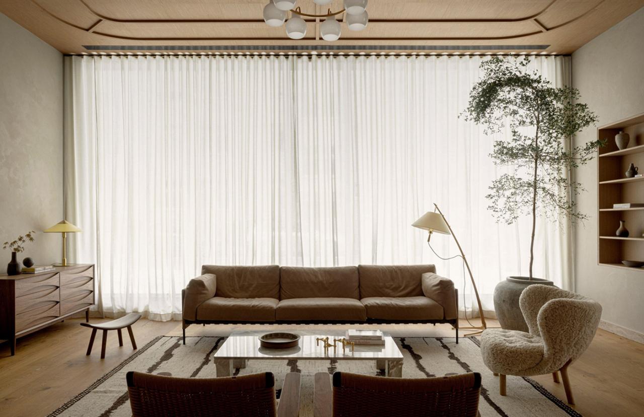 Zona de receptie si lounge cu canapea maro, copac interior si perdele albe la Puro Varsovia