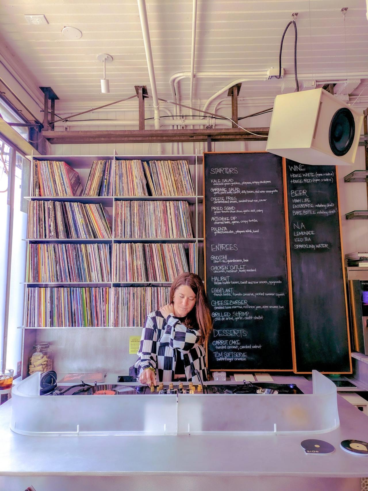 Standul de DJ din aluminiu lustruit cu colectia de viniluri si tabla neagra cu meniul zilei