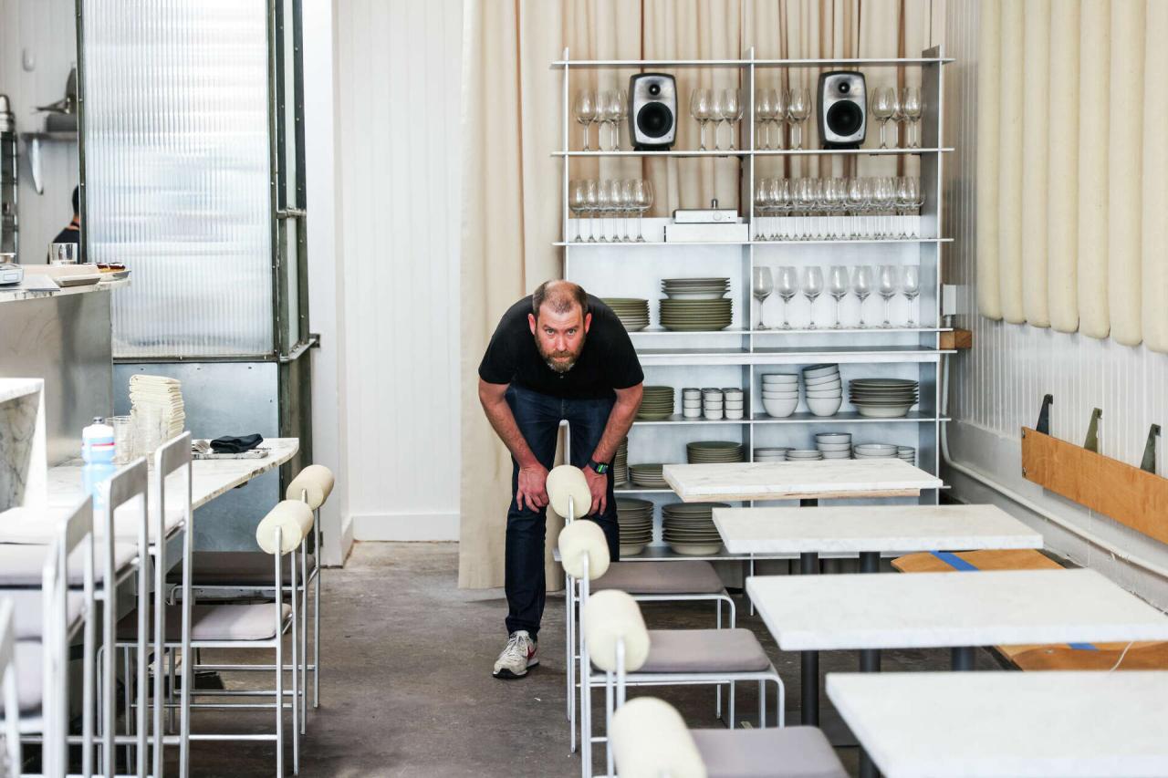 Zona de dining cu mobila metalica custom, perdele din canvas crem si rafturi deschise