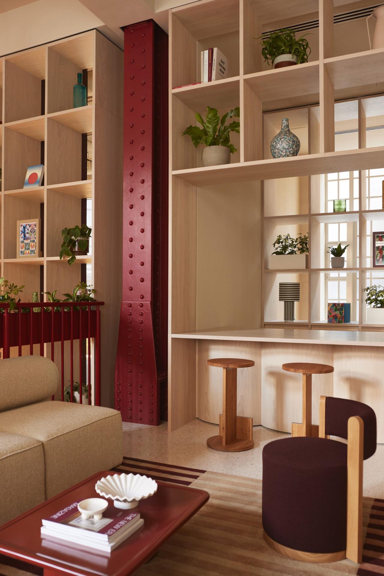 Zona lounge cu coloana metalica rosie nitata si rafturi din lemn deschis