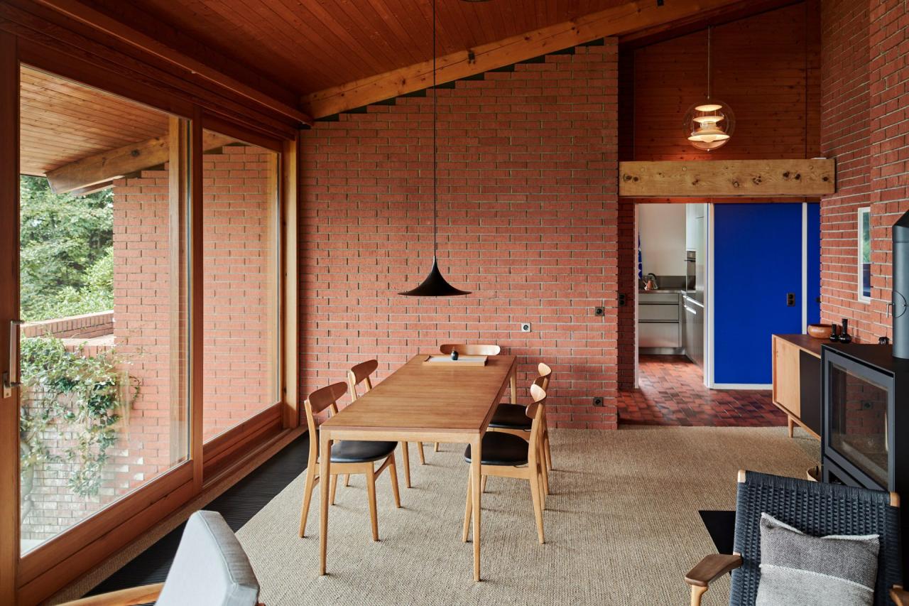 Zona de dining a casei din Vernate cu pereti din caramida aparenta, usa albastra Le Corbusier si vedere la gradina