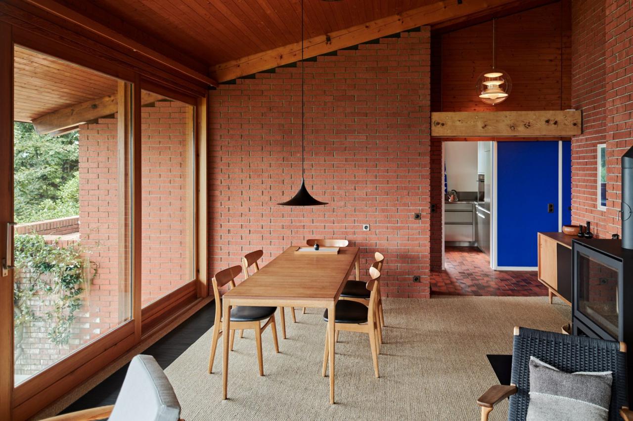 Living-dining cu pereti din caramida si usa albastra Le Corbusier