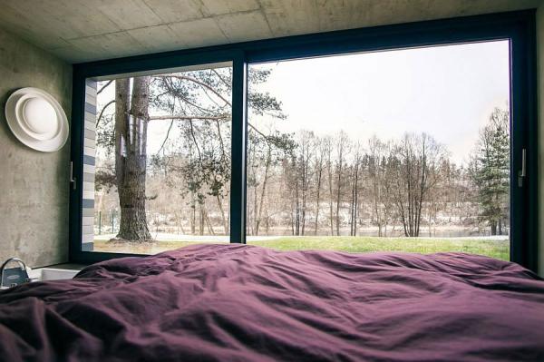 Plush-bedroom-of-the-home-with-concrete-walls-and-lovely-forest-view