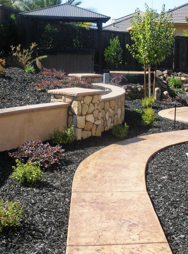 backyard-rock-retaining-wall-planter-stamped-concrete-path